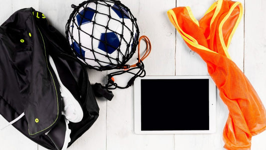 Soccer cleat inside a sports bag with a soccer ball and water bottle on a table