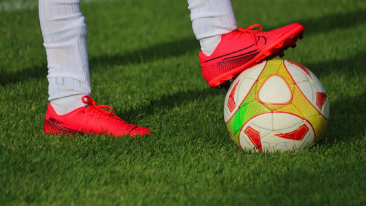 Soccer player standing with the ball under his feet on the field.